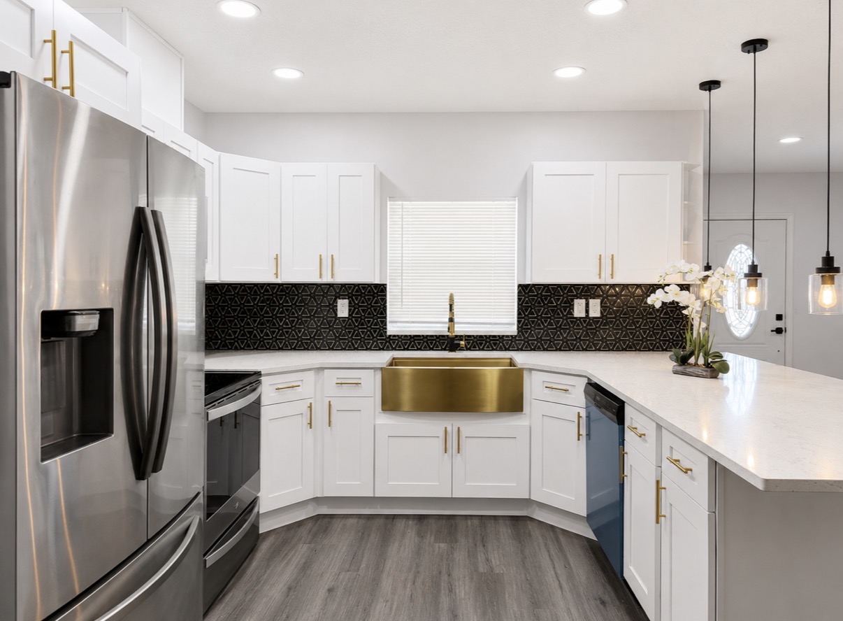 Modern white kitchen with brass farmhouse sink and black backsplash