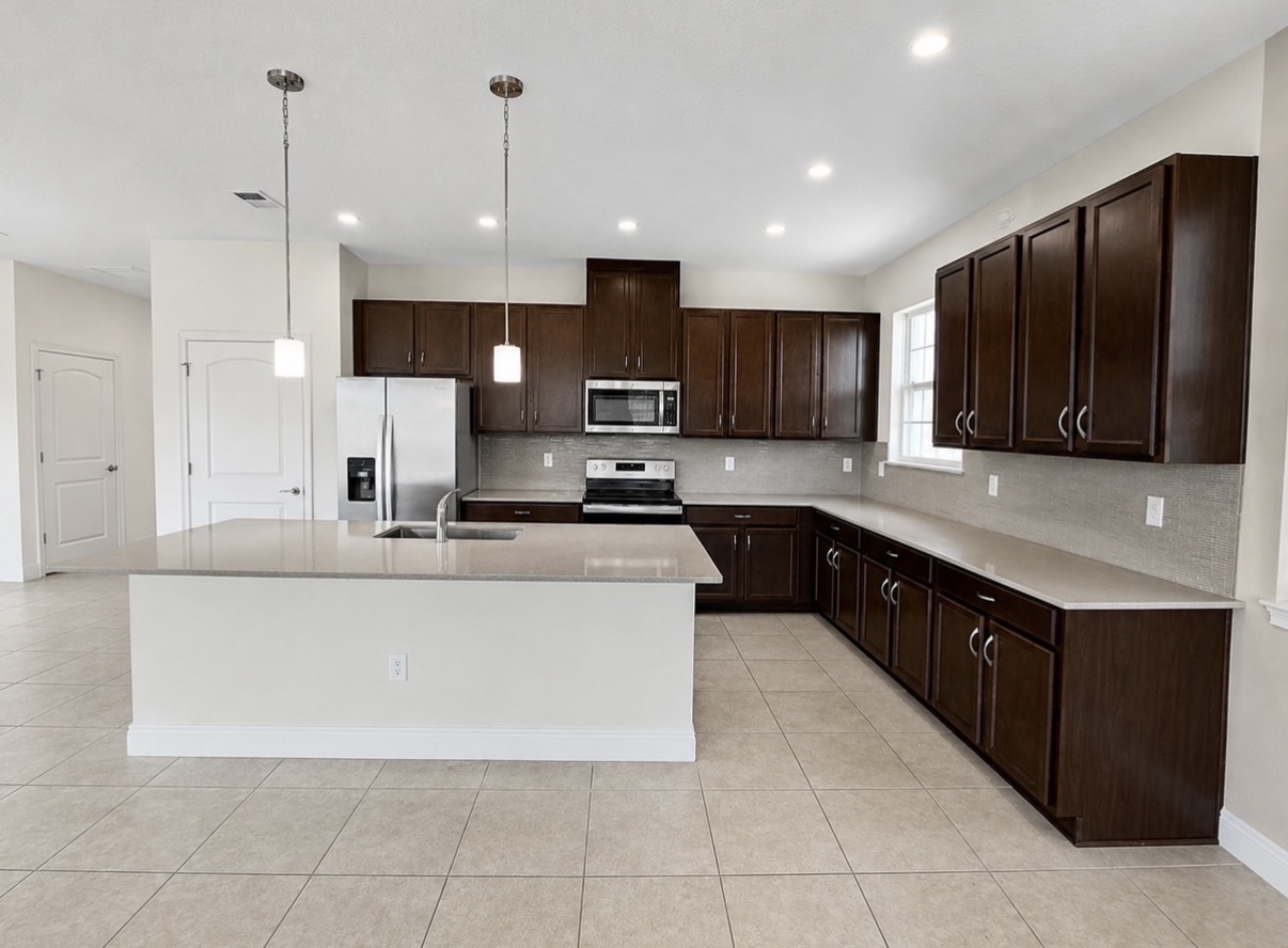 Spacious kitchen with large quartz island and dark wood cabinetry